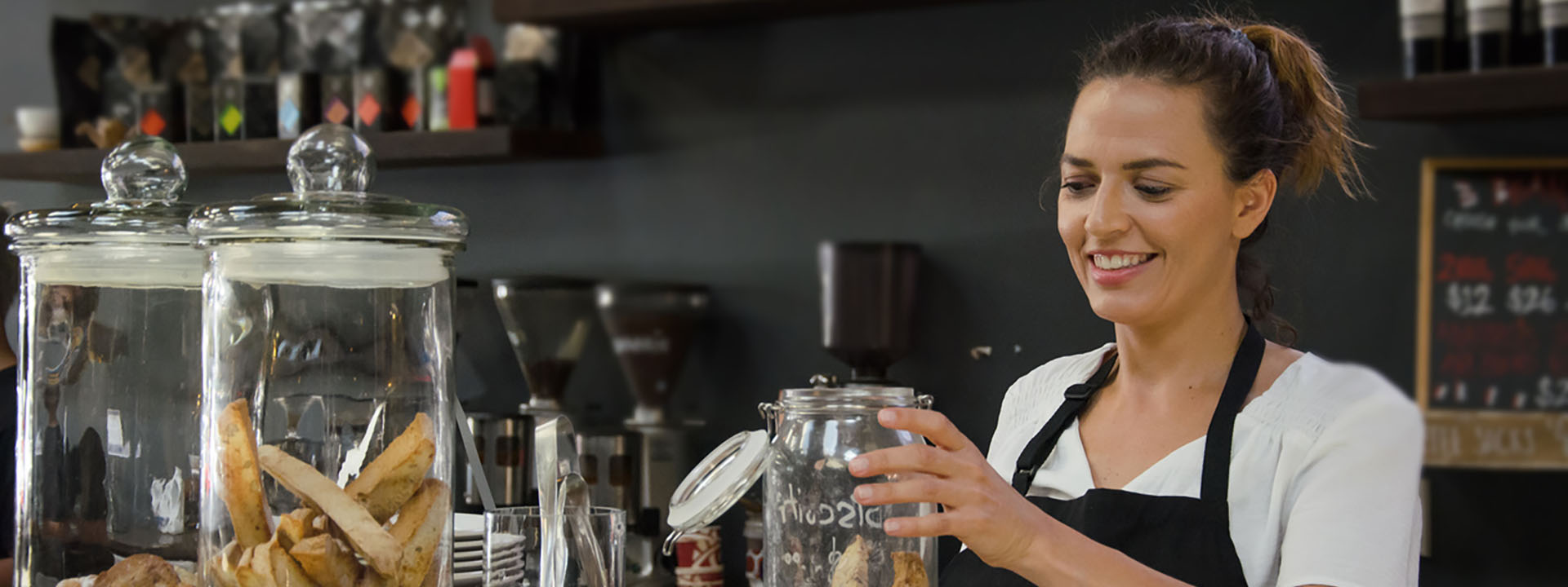 Small business owner preparing coffee at her café counter